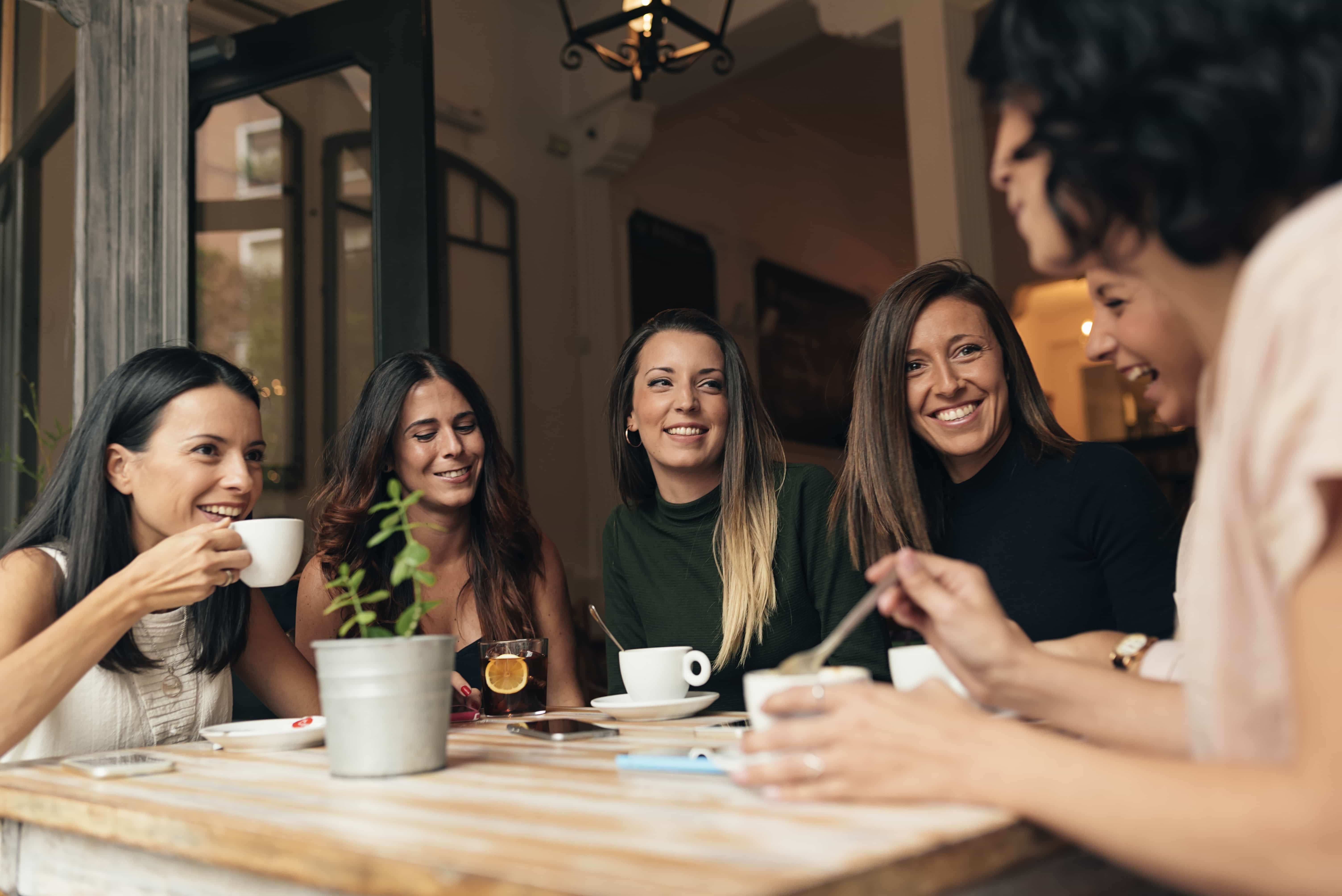 Six beautiful women drinking coffee and chatting. 
